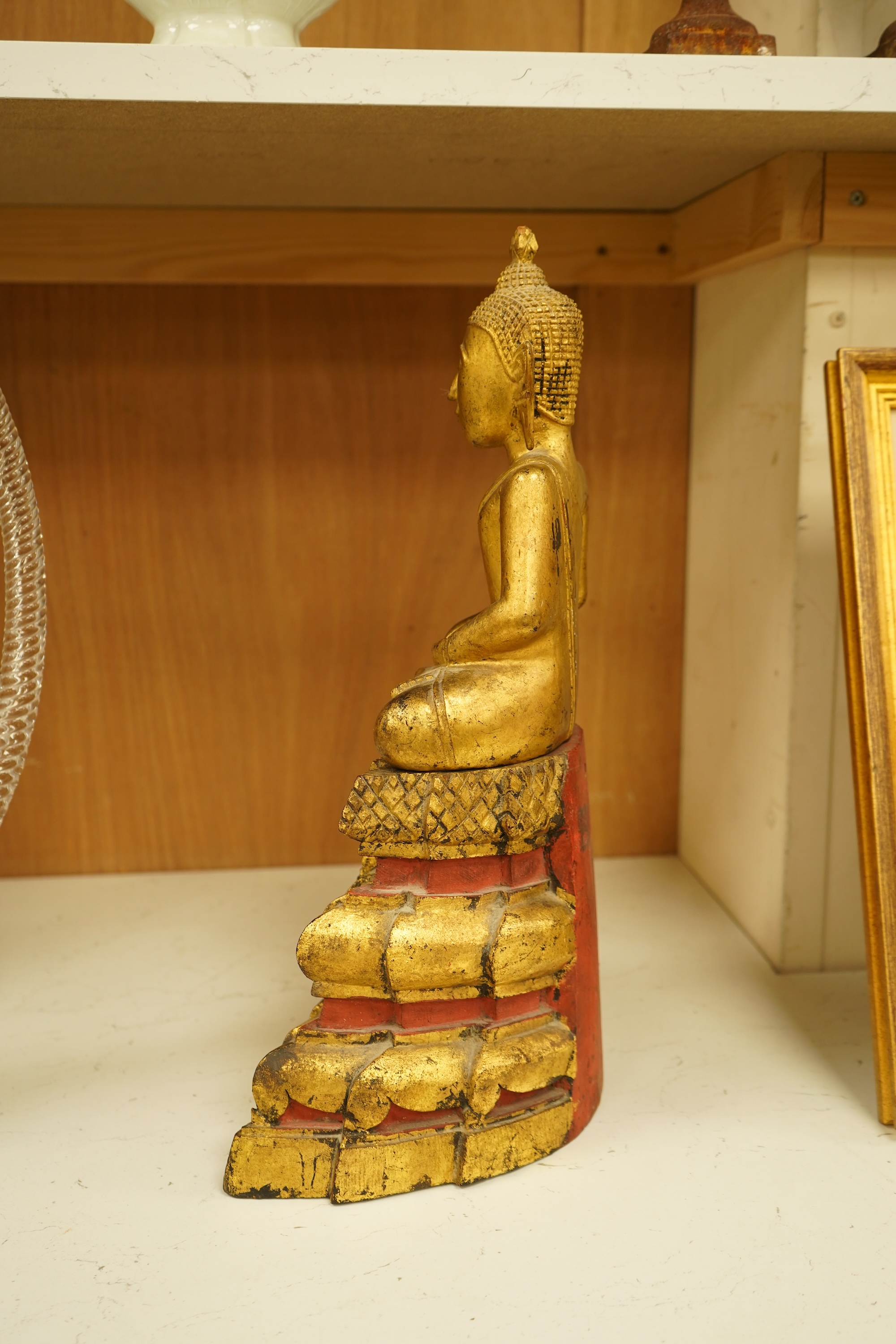 A 19th century Burmese giltwood figure of seated Buddha, 40cm high